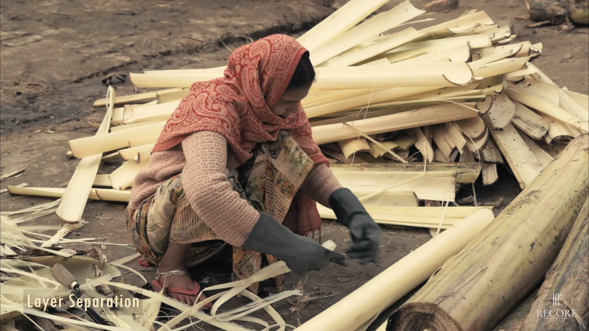 A rural woman separating layers of banana pseudostem by hand at a collection site